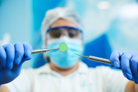 Dental instruments in the hands of a blurred female dentist doing dental examination on a blurred...
