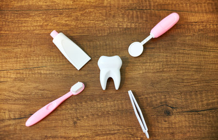Flat Lay composition with toy dental tools for oral care. A toy white tooth, a toy dental mirror,...