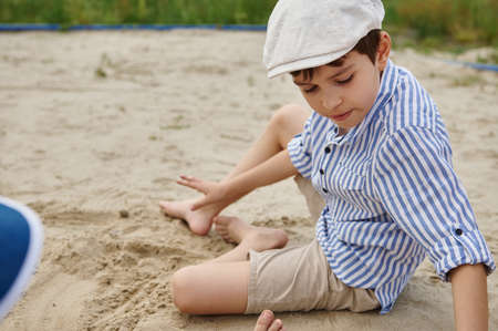 School boy playing on the sand. Outdoors summer holidays. Summer campの写真素材