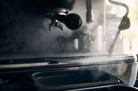 Close-up of a professional steel coffee machine releasing steam and ready to brew coffee drinksの写真素材