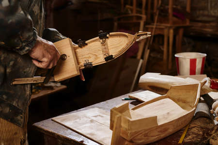 Wooden models of ships on the carpenter's desk against the background of a working craftsman. The...