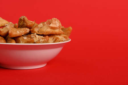 Isolated studio shot on red background of cropped plate with delicious Arabian Moroccan dessert for...
