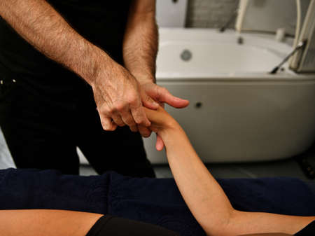 Close-up of professional masseur massaging woman's hand in spa salonの写真素材