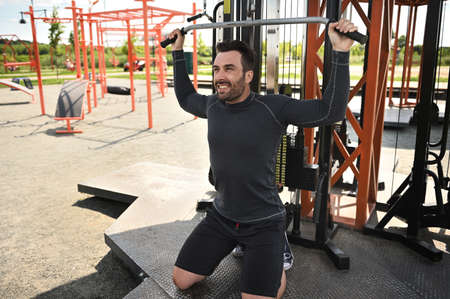 A handsome middle-aged European athlete goes in for sports, shakes his shoulders and back muscles on...
