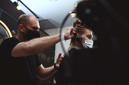 A hairdresser focused on combing hair of beauty salon customer for furthers cutting. Side view of haircuttingの写真素材