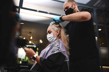 Hairdresser stylist working with compliance with quarantine safety measures when dyeing the salon...