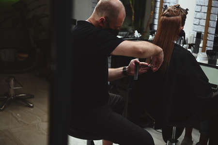 A master of hairstyles cutting woman's hair in beauty salon. Haircutting. Hairdressing.の写真素材