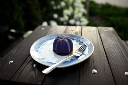 A delicious luxury raw vegan mousse dessert served on a plate with fork on a wooden table on summer terrace of a cozy cafeteriaの写真素材