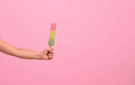 Healthy vegan ice cream in hand of a baby girl isolated on pink wall background with copy space . Summer dessert and cheerful summer mood conceptの写真素材