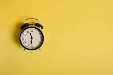 Back to School and Teachers Day Concepts, Business, Organization, Time Management. Vintage black alarm clock on yellow background with copy space to add text.の写真素材
