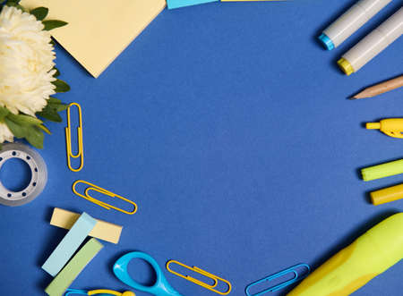 Flat lay of school office accessories in yellow shades, isolated on blue background, copy space....