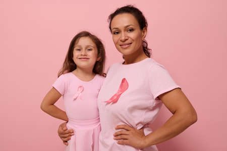 Gorgeous women of two generations, African American lady and European baby girl, in pink clothes and pink ribbon, support cancer survivors. Medical Concept October 1. World Breast Cancer Awareness Dayの写真素材