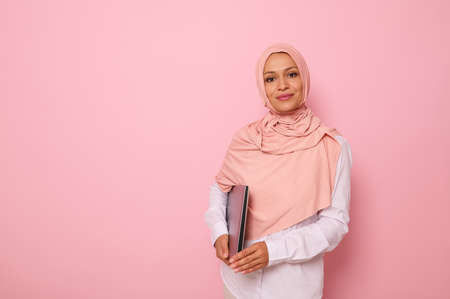 Isolated confident business portrait on colored background of Arab muslim pretty woman with covered...
