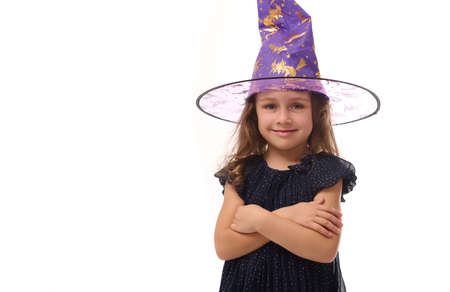 Portrait of winsome witch smiling happy girl wearing a wizard hat and dressed in stylish carnival...