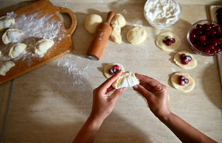 Close-up shot of pastry chef hand sculpting cherry dumplings on kitchen countertop background....