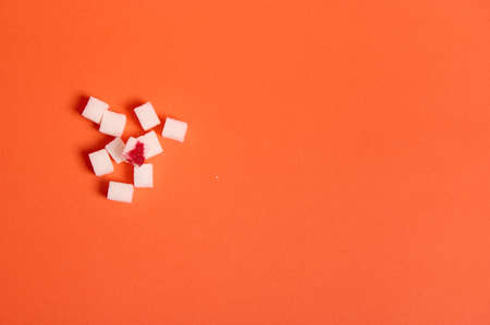 Flat lay studio shot of refined white sugar cubes with blood drop isolated over colored orange background with copy space for medical advertising. World diabetes day awareness concept, 14 Novemberの写真素材