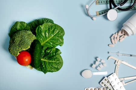 Diabetes Awareness Day concept, 14 November. Scattered pharmaceutical pills, blisters of tablets, insulin syringe, stethoscope, measuring tape, refined sugar on blue background, healthy vegan food.の写真素材