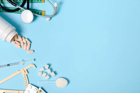 Scattered pharmaceutical pills, blisters of tablets, insulin syringe, stethoscope, caliper, measuring tape, refined sugar on blue background, copy space. Diabetes Awareness Day, 14 November. Flat layの写真素材