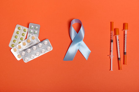 Insulin syringes, pharmaceutical pills and blue ribbon, symbolic bow color of World Diabetes awareness Day, isolated on orange background. Copy space for ad. Medical Concept 14 for November. Flat lay.の写真素材