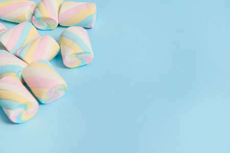 Flat lay minimalistic composition of colorful sweet marshmallows in the corner of a blue pastel background with copy space for advertising.の写真素材