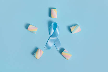 Colorful multi colored sweet marshmallows laid out in a five-pointed star shape with a blue awareness ribbon inside on a pastel background with copy space. Concept for World Diabetes Day 14 Novemberの写真素材