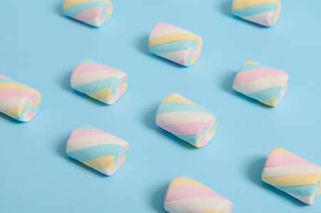 Marshmallows colorful pattern on a blue pastel colored background with copy space for advertisement. Food background, flat lay minimalistic compositionの写真素材