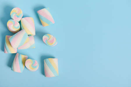 Colorful sweet marshmallows in the corner of a blue pastel background with copy space for advertising. Flat lay minimalistic compositionの写真素材