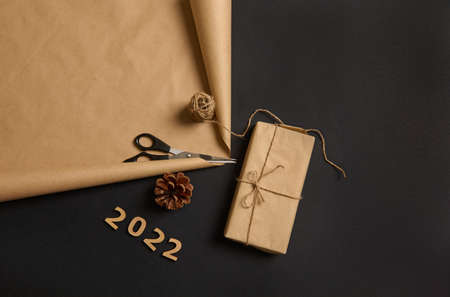 Flat lay composition of a Christmas present, wooden numerals 2022, pine cone, scissors and rope on...