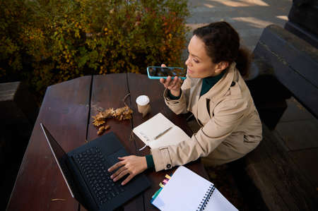 High angle view of a pretty woman, confident business lady sitting in an outdoor wooden cafeteria in...