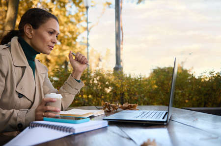 Beautiful business woman concentrated on distant work, looks at the screen of laptop and enjoys...