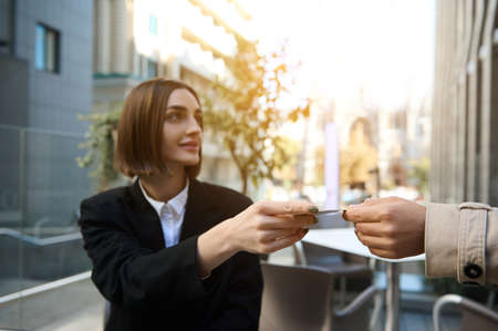 Young woman hands over a plastic credit card for payment. Focus on credit card.の写真素材