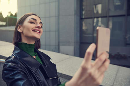 Close-up lifestyle portrait of beautiful funny young brunette with stylish short hair, holding...
