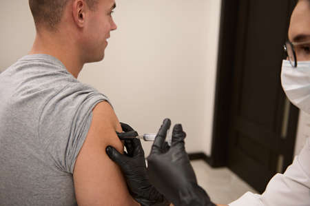 Athlete man getting antiviral vaccine against virus or flu at hospital. Immunization of population to fight epidemic and protecting from spread of viral infection. Voluntary vaccination conceptの写真素材