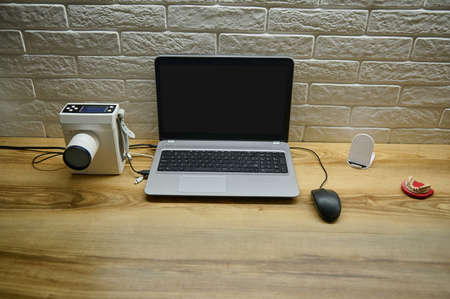 Laptop with blank monitor screen with copy ad space, portable dental x-ray machine to create...