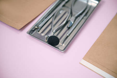 A set of sterile stainless steel instruments for professional pedicure on colored background with...
