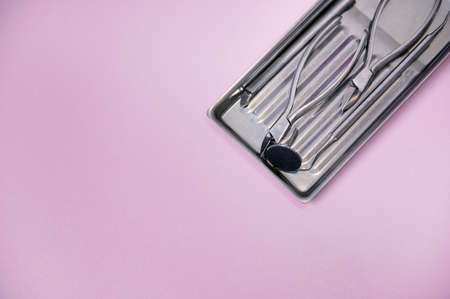 Close-up of a set of sterile stainless steel instruments for professional pedicure on colored background with copy space. Chiropody tools.の写真素材