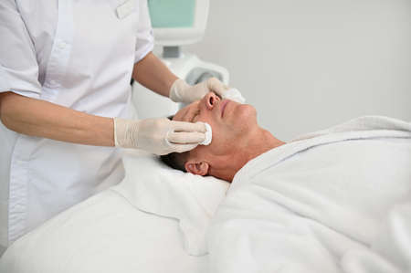 Close-up of a mature male client of spa salon receiving professional beauty treatment....