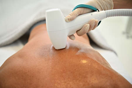 Radio wave lifting at spa clinic. Close-up of the back of unrecognizable mature man receiving...