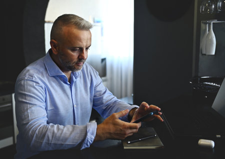 Confident prosperous middle aged businessman, freelancer browsing , surfing on websites, using...