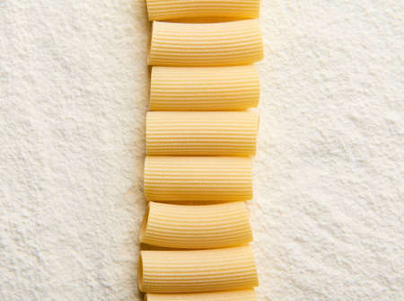 High angle view of neatly arranged whole wheat Italian pasta in a row on a floured surface with copy space for adの写真素材