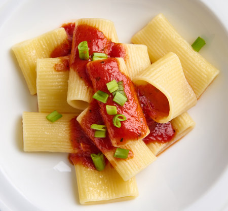 Flat lay. Close-up of a healthy vegan meal of a traditional cooked Italian pasta with tomato sauce and green onion garnish. Healthy eating concept. Italian menuの写真素材