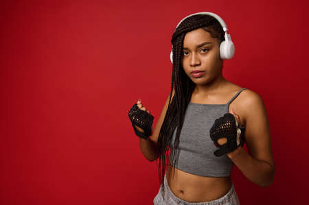 Fitness young African athlete young woman boxer with fit body preparing for boxing training. Women self defense. Cardio training concept in red colored background with copy space for advertisingの写真素材