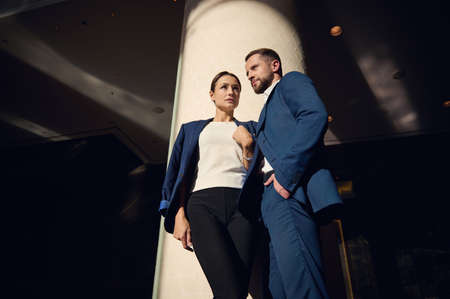 Charming handsome young people, business partners, colleagues, flirting together standing close to each other in the lobby of luxury hotel. Love affairs at work, people, business, intrigues conceptの写真素材