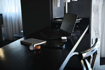 Office accessories, laptop, earphones on the box, watch, mobile phone and gray notepad on wooden...
