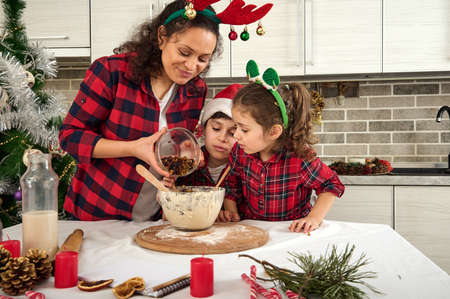 Beautiful happy loving mother and her adorable cheerful children, son and daughter cooking together...