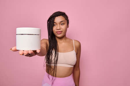 Soft focus on a white container, jar with cosmetic product in the outstretched hand of a pretty...