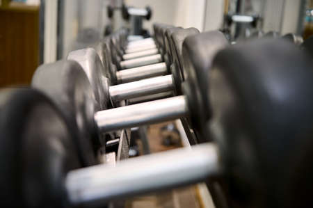 Close-up of dumbbells on rack in sport fitness center background. Steel dumbbell set. Workout training and fitness gym concept. Healthy and well being concept. Sport equipment and tool themeの写真素材