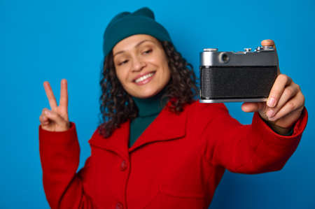 Focus on retro style photographic equipment vintage camera in the hands of blurred pretty woman,...