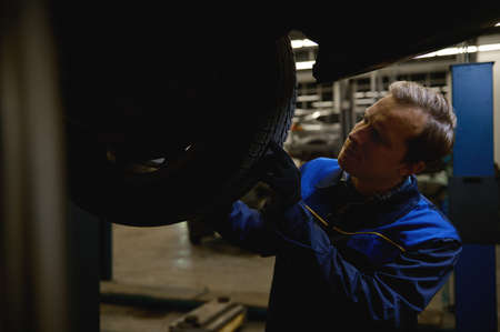 Mechanic checking tire in maintenance service center. Technician or engineer professional work for...