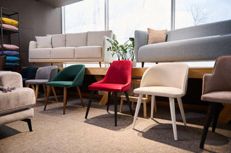 Beautiful modern retro style chairs displayed for sale in the furniture store showroom with settees,...